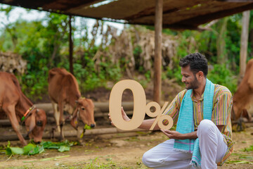 Banking or financial concept : Young indian farmer showing zero percent symbol at his cattle farm