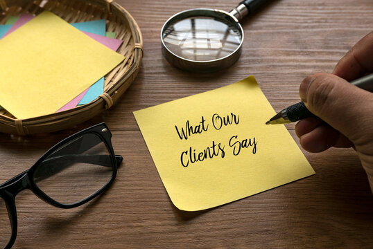 Selective focus of hand writing What Our Clients Say on a yellow paper.