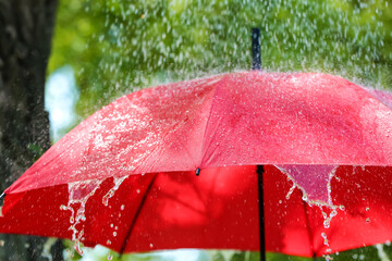 Open umbrella under falling rain drops outdoors