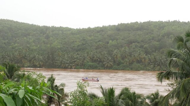View of moving boat in flood water with trees in background