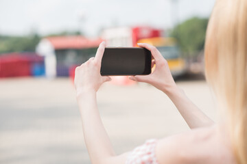 Beautiful caucasian blonde girl holding a smartphone in her hands and taking picture