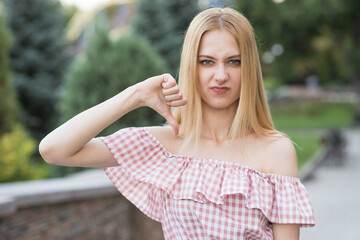 Portrait of a dissatisfied blonde caucasian girl. Lady showing dislike gesture