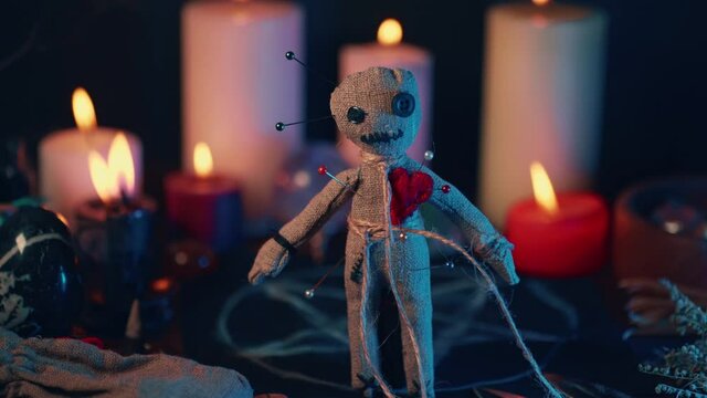Voodoo Magic concept. Voodoo doll studded with needles with pierced rag heart and around burning candles. Spooky or eerie magical esoteric ritual.