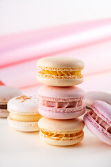Colorful pastel french macaroons or macarons  on white and pink background