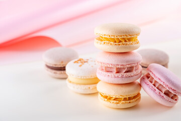 Fototapeta na wymiar Colorful pastel french macaroons or macarons on white and pink background