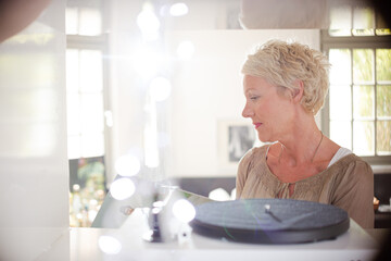 Older woman playing vinyl record on turntable