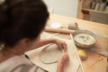 Ceramic artist shaping clay slab
