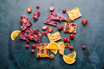 Handmade chocolate bars with fruits and nuts on dark background
