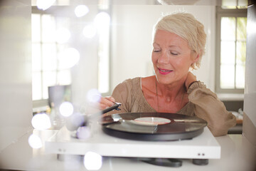 Older woman playing vinyl record on turntable