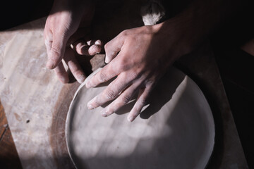 Fototapeta na wymiar The process of making ceramic plate, man pinching clay