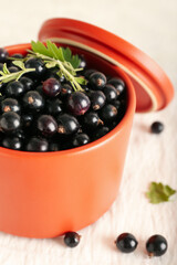 Bowl with ripe black currant on light background, closeup