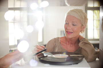 Older woman playing vinyl record on turntable
