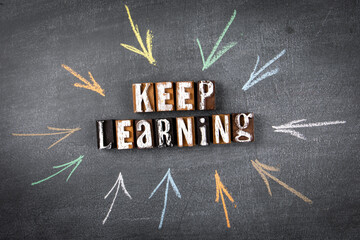 Keep Learning concept. Letters of the alphabet on a chalk board. Drawn arrows
