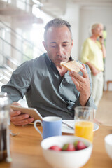 Older man using digital tablet at breakfast table