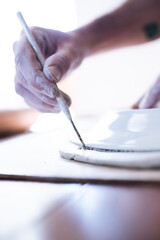 Ceramist doing pottery at home. Man is sculpting a plate