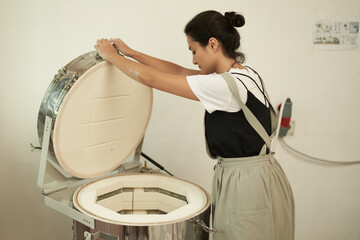 Artisan with electric oven in pottery workshop
