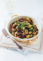 Gnocchi with onion and mushrooms. Bright wooden background. Copy space.	