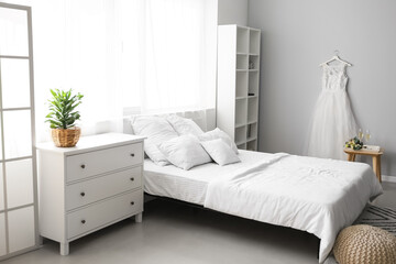 Interior of bedroom with beautiful wedding dress prepared for ceremony