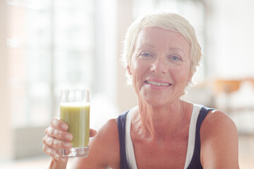 Older woman drinking juice on exercise mat