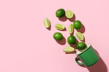 Tasty limes and mug on color background