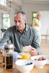 Fototapeta na wymiar Older man using digital tablet at breakfast table