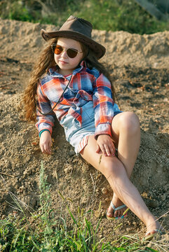 A little fashionable girl in a cowboy hat in nature .