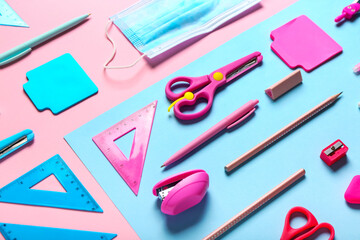 Stationery supplies with medical mask on color background