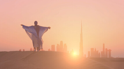 Arabic woman weared in traditional UAE dress - abayain rising her hands on the sunset at a desert...