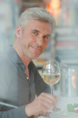 Smiling older man toasting with white wine