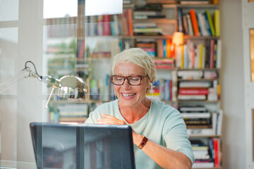 Fototapeta na wymiar Businesswoman smiling at computer in home office