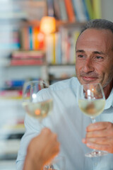 Older man drinking white wine at dinner