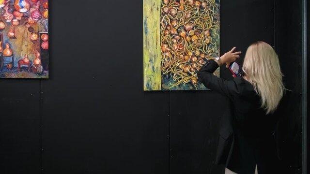 young woman is taking photo of painting in fine art museum