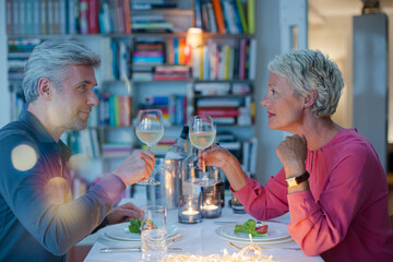 Older couple toasting each other at romantic dinner
