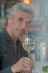 Smiling older man toasting with white wine