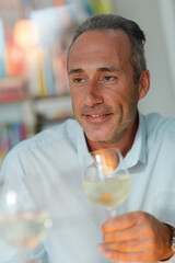 Older man drinking white wine at dinner