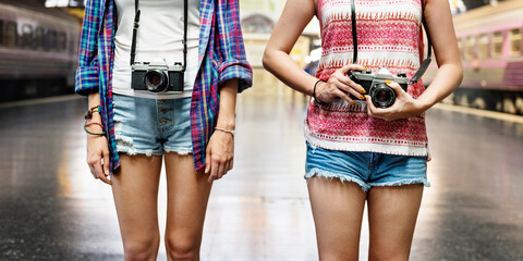 Obraz na płótnie Canvas Two tourist women standing at train platform with camera
