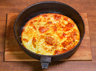 Freshly scrambled eggs in rustic pan on the cooking table
