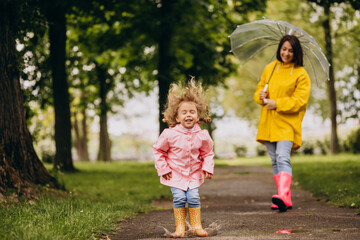 Fototapeta na wymiar Mother with daughter walking in the rain under the umbrella