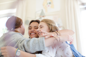Three teenage girls embracing in bedroom