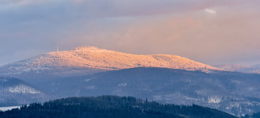 Snieznik Massif, Czarna Gora peak, snow-covered forests in the mountains at sunset.