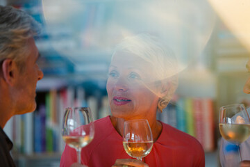 Older friends toasting each other with white wine