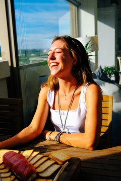 Young woman laughing while having dinner at home during weekend