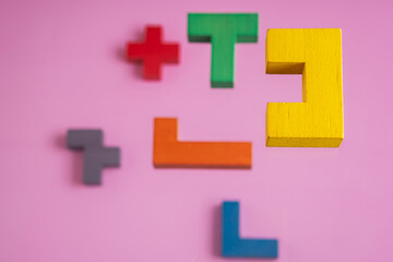 Different colorful shapes wooden blocks on pink background, 3D. Concept of creative, logical thinking.