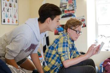 Obraz premium Two teenage boys having fun while using digital tablet