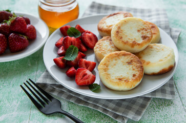 Cottage cheese pancakes, ricotta fritters on ceramic plate with  fresh strawberry.
