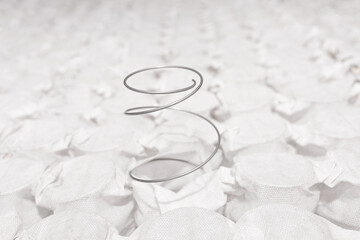 Pocket independent spring sewn in white span-bond mattress base with one metal spring poking out