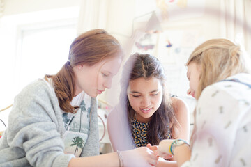 Three teenage girls relaxing in bedroom