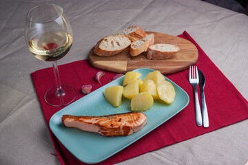 Escena gastronomía salmón con patatas, pan y vino blanco.