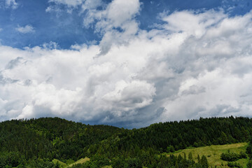 Fototapeta na wymiar Clouds over the Ochotnica Gorna vilage hills during summer day