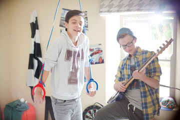 Two teenage boys having fun and playing electric guitar in room